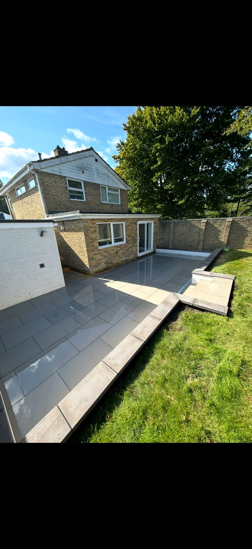 Grey patio with steps to lawn by Burton Builds patio specialists
