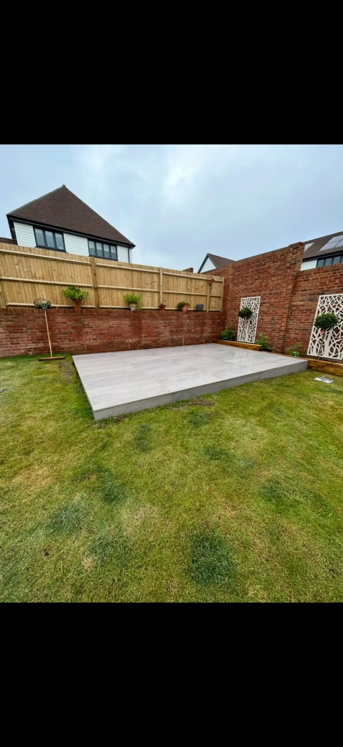 Porcelain patio base with decorative garden screens by Burton Builds